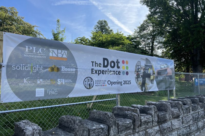 Street view from an angle of The Dot Experience groundbreaking banner highlighting project partners.