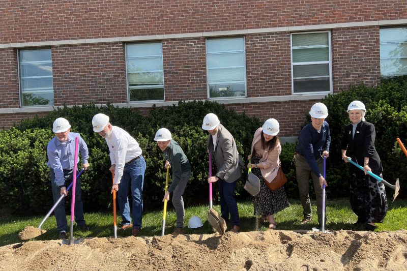 The Solid Light team wearing hard hats and standing on a mound of dirt with colorful shovels turning dirt to break ground on The Dot Experience.